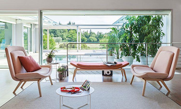 Salon lounge avec canapé Athos et fauteuils roses devant une véranda