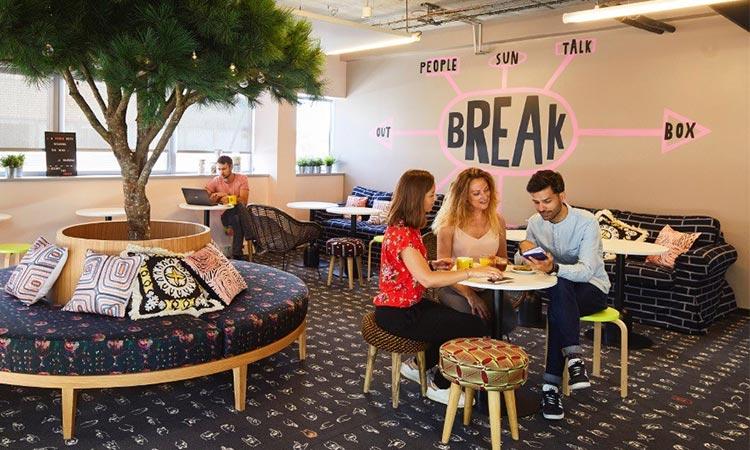 Espace de coworking convivial avec arbre, canapés et coin pause