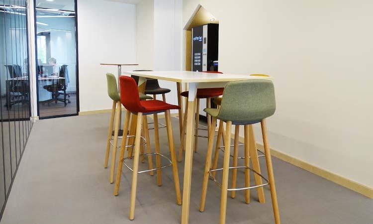Espace de pause avec table haute blanche et tabourets Keira colorés