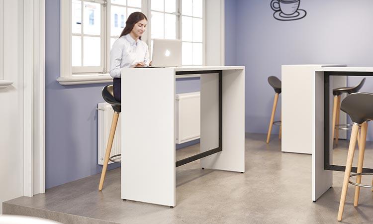 Femme travaillant debout à un bureau haut dans un espace mauve