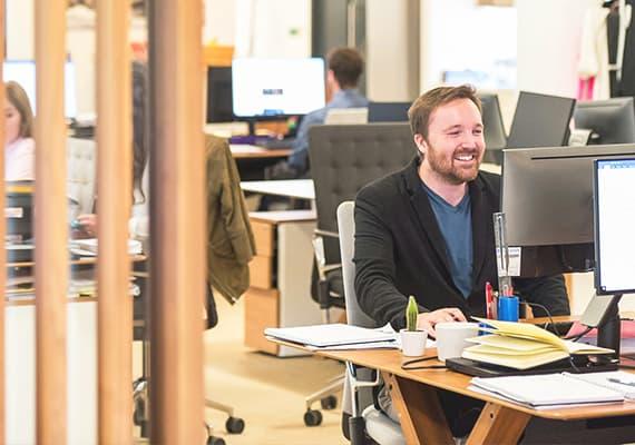 Homme souriant travaillant à son bureau dans un open space