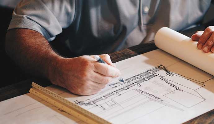 Un architecte qui dessine un plan 2D sur une feuille