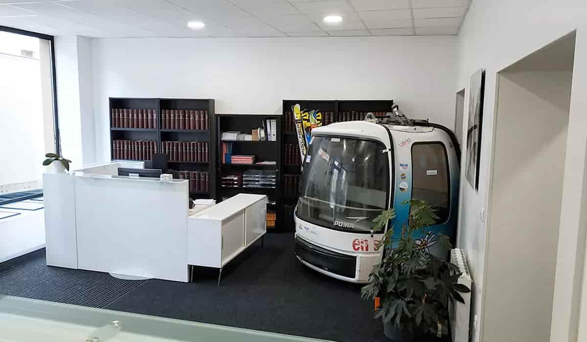 Espace d\'accueil avec banque blanche, bibliothèque et cabine décorative